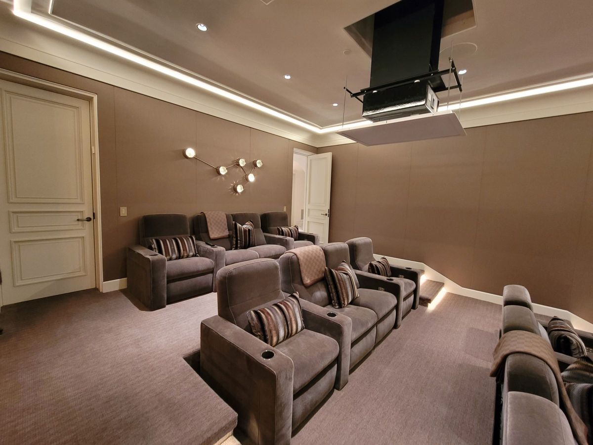 Tiered home theater seating with a ceiling-mounted projector and accent lighting