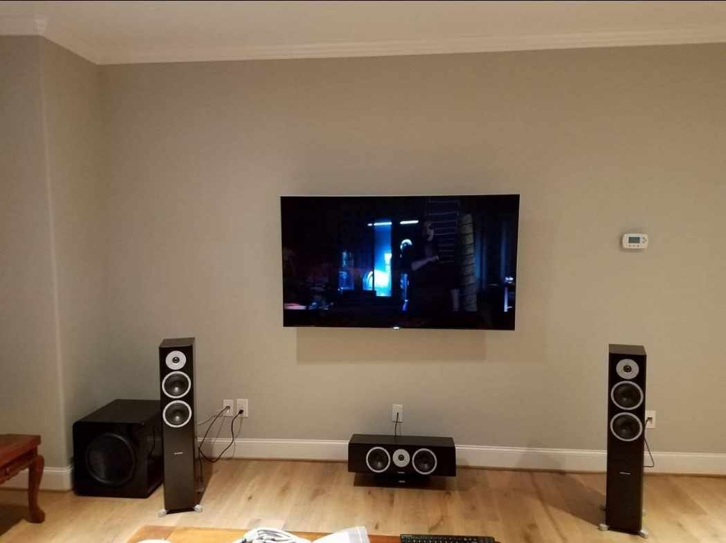 Living-room listening system with floorstanding speakers and a wall-mounted television