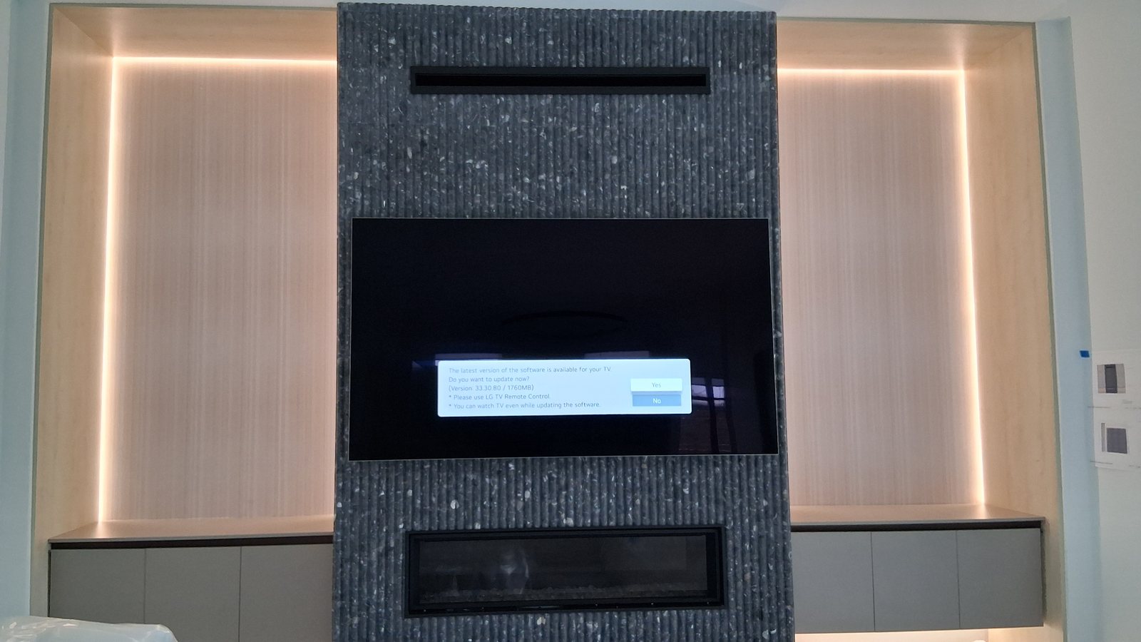 Display built into a stone surround between backlit wood panels