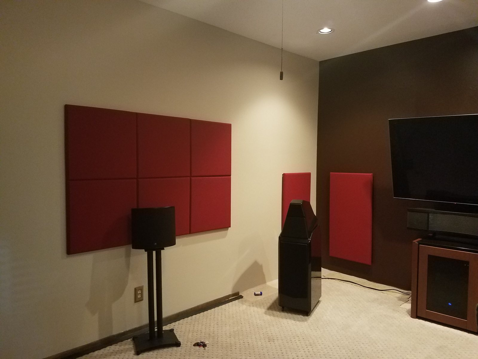 Media room with red acoustic panels, tower speakers and a wall-mounted television
