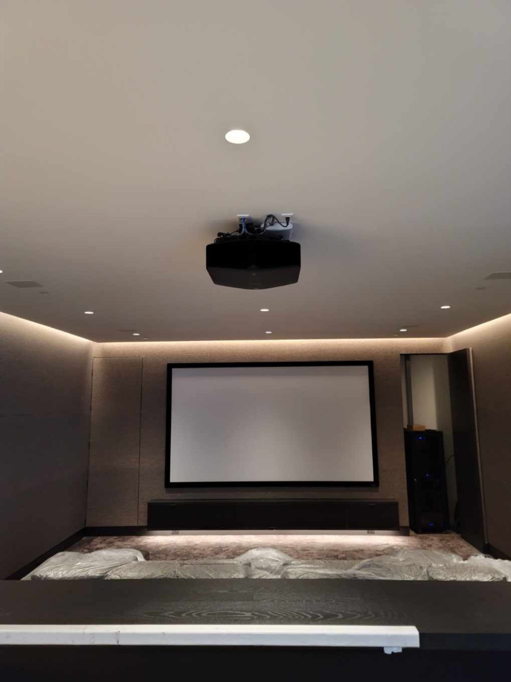 Montrose dedicated theater with ceiling-mounted projector, framed screen, cove lighting and a separate equipment rack