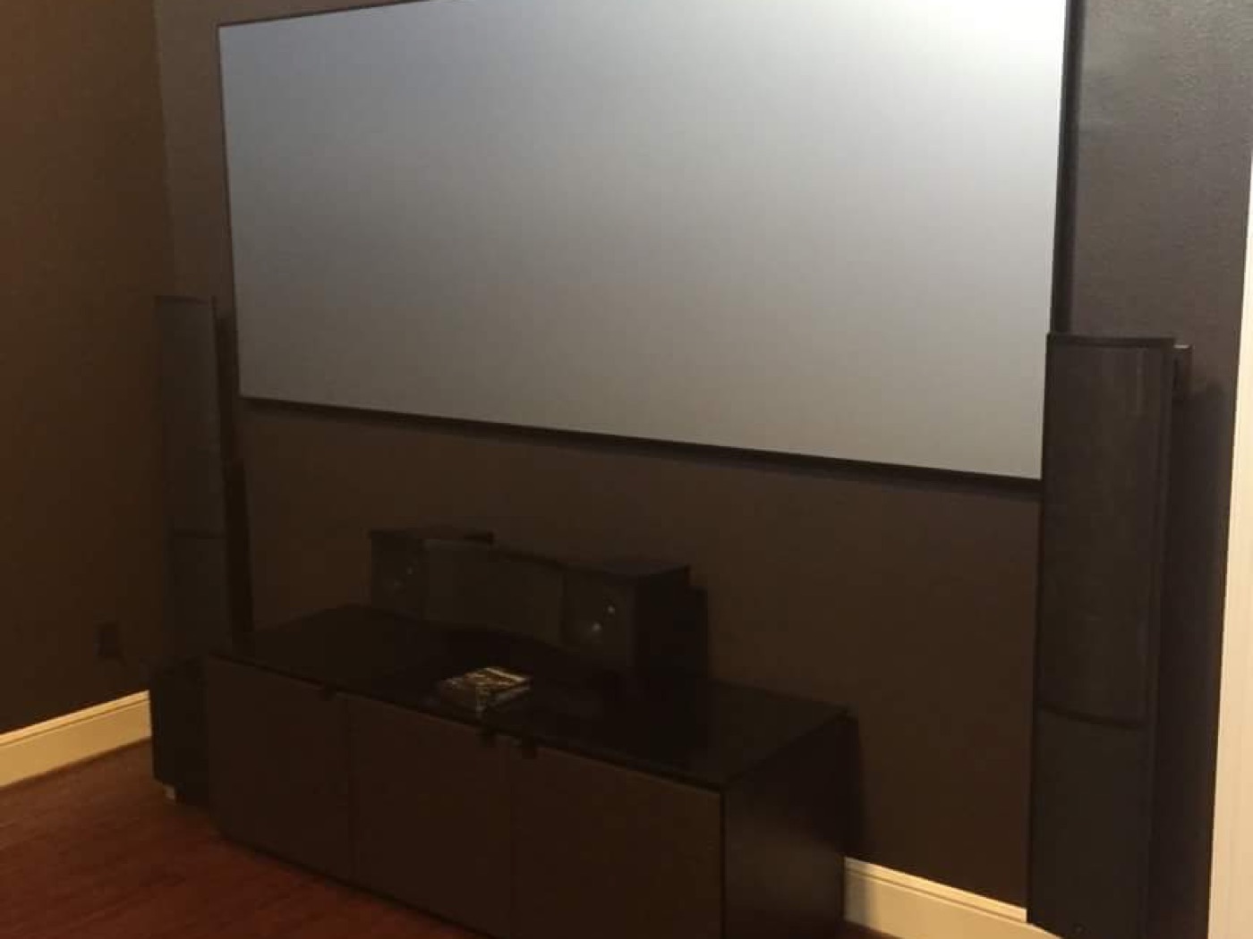 Fixed projection screen with slim on-wall speakers and a center channel in a Richmond, Fort Bend County home