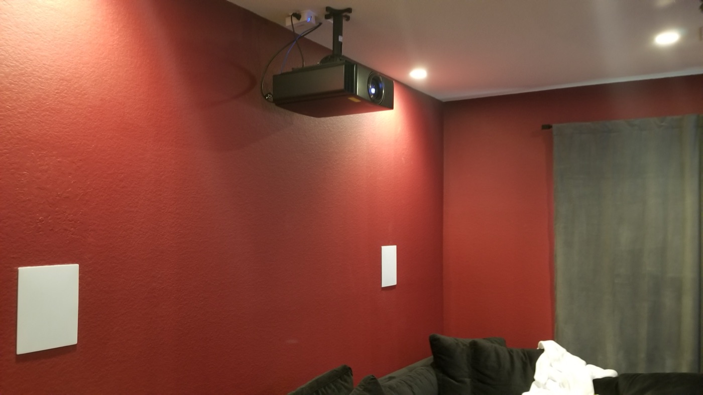 Ceiling-mounted projector and flush in-wall speakers in a red-walled Tomball media room