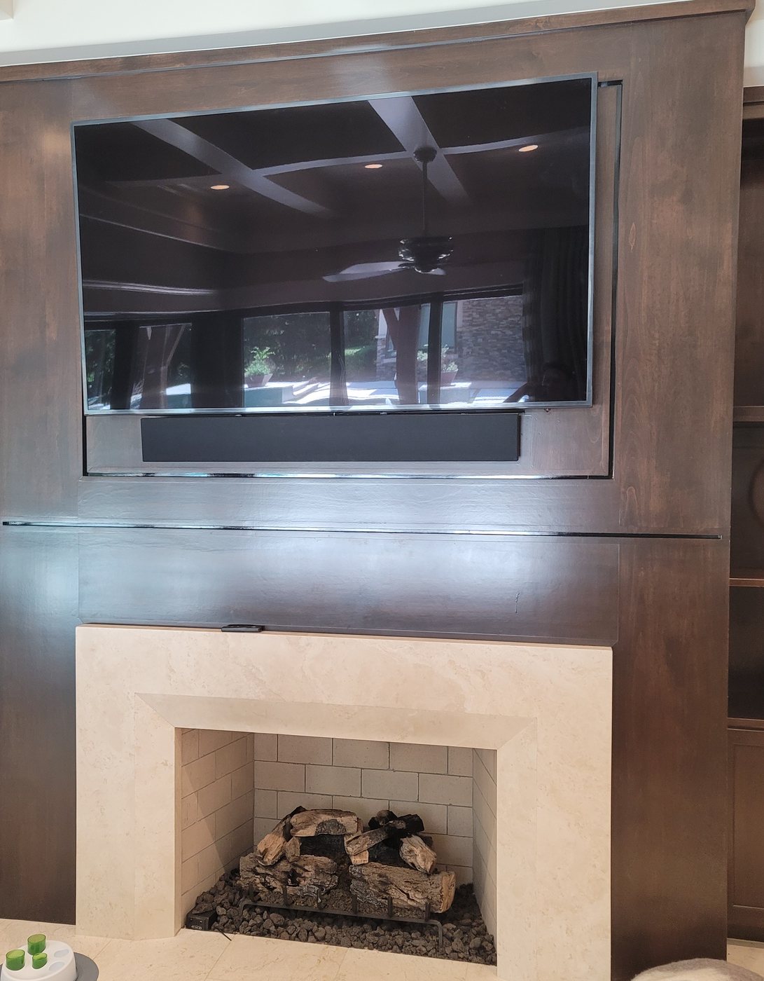 Television built into a dark wood surround above a fireplace in a Carlton Woods home, The Woodlands