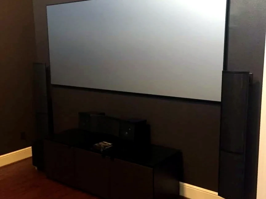 Dark home theater room with projection screen and tower speakers visible on both sides
