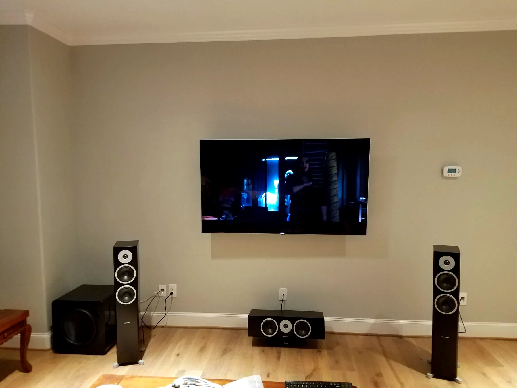 Surround sound TV room with wall mounted display left and right speakers center channel and subwoofer visible