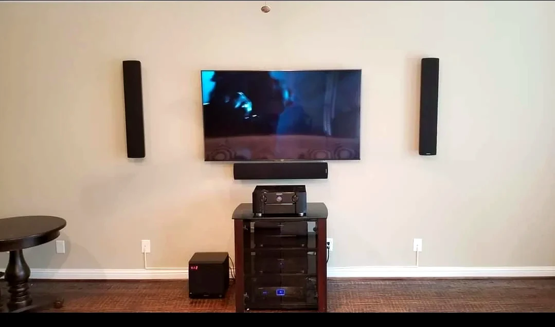 Media room with wall speakers TV subwoofer and AV equipment rack visible
